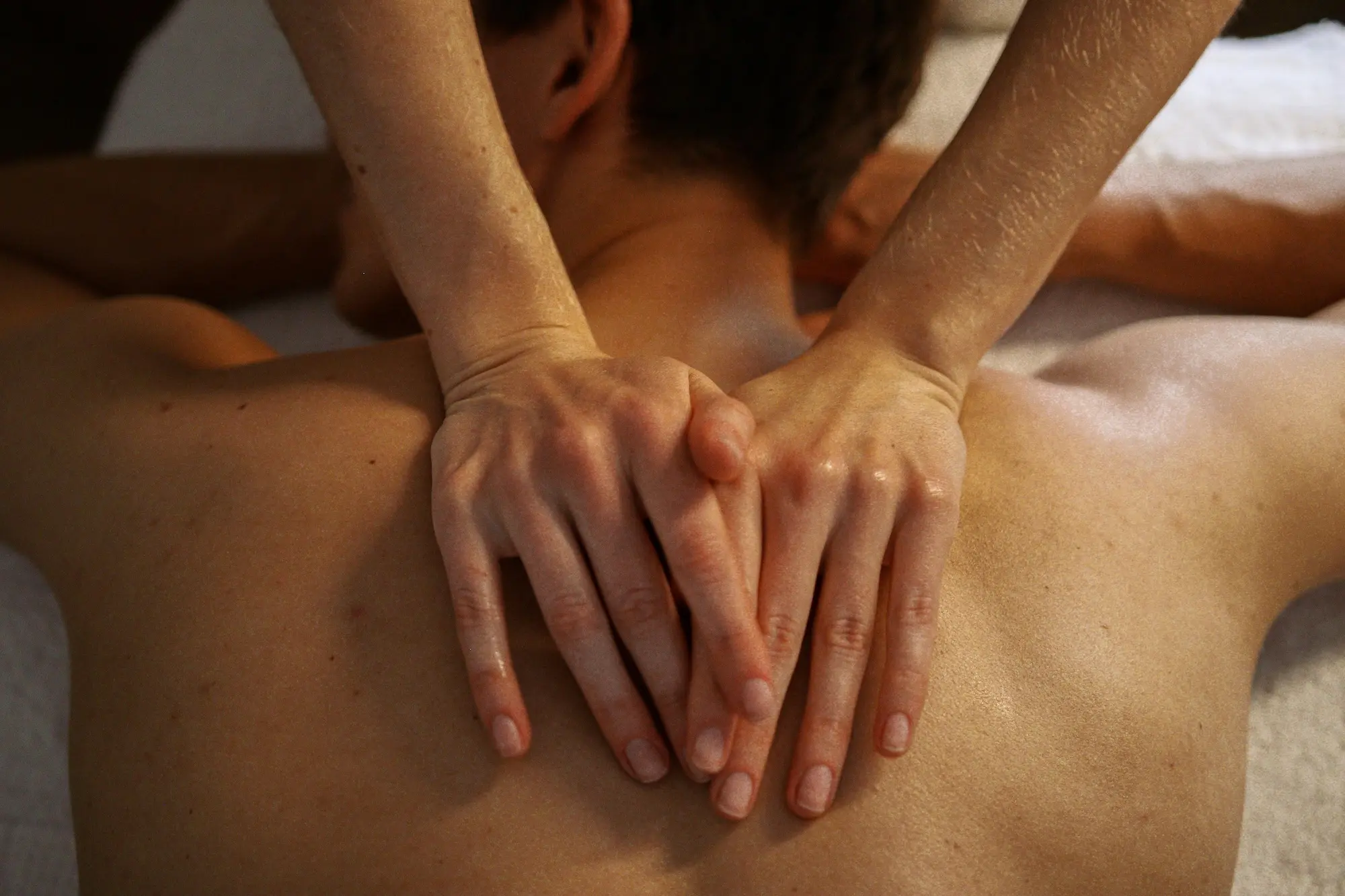 Manos realizando masaje sensual con aceite tibio
